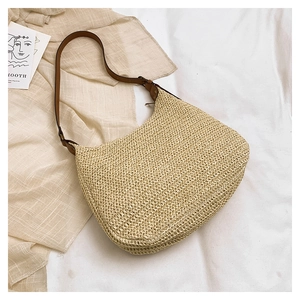 Detail of hand-woven beige straw hobo bag with brown leather shoulder strap and buckle