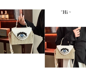 Détail du sac boîte en paille avec rabat en cuir blanc et décoration d'œil bleu
