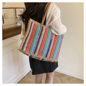 Detail of colorful striped woven straw tote bag with brown leather shoulder straps