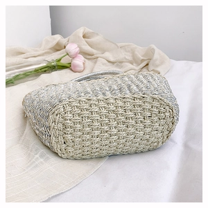 Detail view of handmade straw bag featuring silver metallic thread and woven textures
