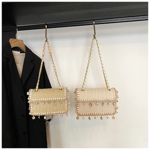 Detail of straw woven crossbody bags with seashell fringe and elegant chain straps