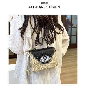 Détail du sac bandoulière en paille avec perles œil grec et pompon sur modèle