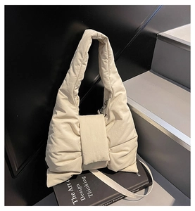 Detailed view of cream puffer bow bag with soft quilted texture and wide handles