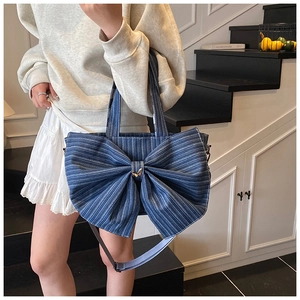 Detailed view of the blue denim tote bag featuring a large bow and adjustable strap