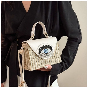 Détail du sac panier en paille avec rabat en cuir blanc et motif œil perlé artistique