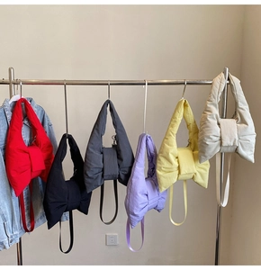 Multiple colorful puffer bow tote bags hanging on a rack showing variety of color options