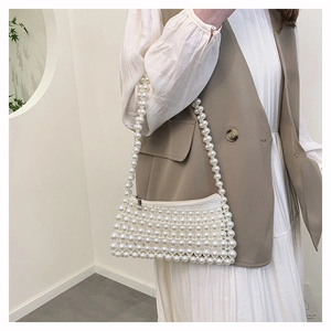 Detail of elegant white pearl beaded shoulder bag with metallic zipper and pearl strap