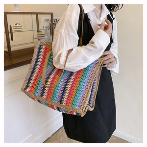 Macro shot of large rainbow woven straw tote bag with brown leather handles and vivid stripes