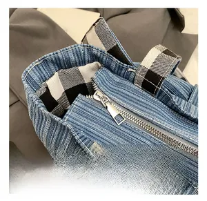 Close-up of blue denim tote bag with silver zipper closure and black-white checkered handle
