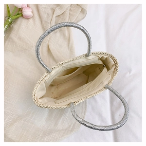 Top view of woven straw beach bag with silver handle and organized fabric interior