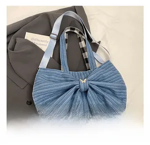 Detail of blue denim tote bag with a large bow design and gold butterfly hardware buckle