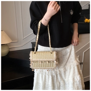 Detailed view of woven straw crossbody bag featuring floral lace trim and chain strap