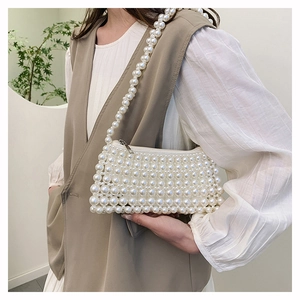 Detail of handcrafted white pearl beaded mini bag with metallic zipper and elegant woven texture