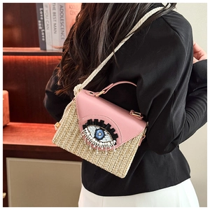 Détail du sac à bandoulière en paille avec motif œil, perles et rabat en cuir rose