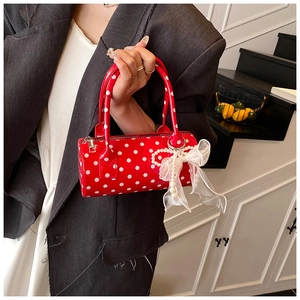 Close-up of red polka dot barrel bag featuring a pearl chain and organza bow detail