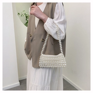 Detail shot of the hand-woven pearl bead texture and secure zipper closure on the bag