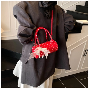 Close-up of red polka dot cylindrical bag with lace bow and pearl pendant details