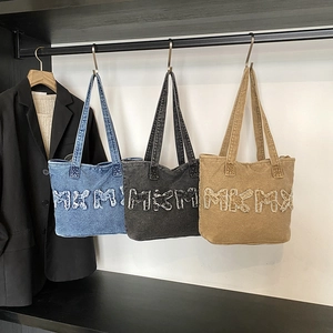 Three oversized denim tote bags in blue, grey, and khaki with frayed letter patchwork
