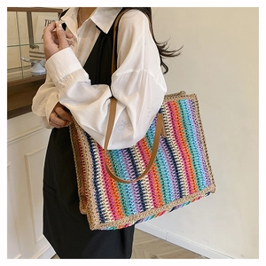 Detailed close-up of rainbow striped woven straw tote bag with brown leather handles