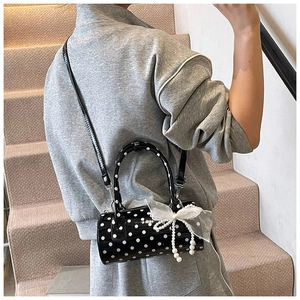 Detailed view of polka dot cylindrical handbag with lace bow and pearl tassel charms