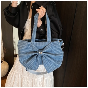 Detail of blue striped canvas tote bag featuring large bow and gold butterfly buckle