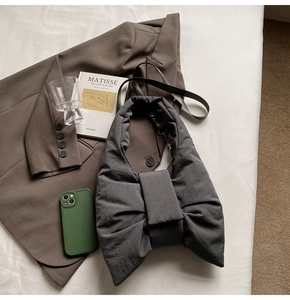 Flat lay of a dark grey quilted bow shoulder bag with nylon texture and adjustable strap