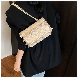 Detail of straw woven crossbody bag with bead accents and gold chain on model