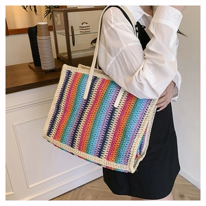 Rainbow woven tote bag with white leather straps shown in a minimalist cafe setting