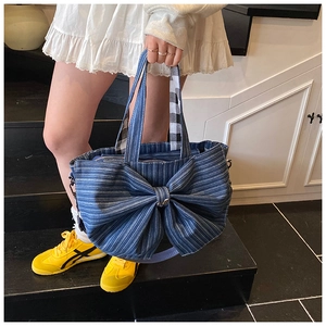 Detail of blue striped denim tote bag featuring a large decorative bow and durable handles