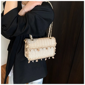 Detail view of woven straw crossbody bag with small shell pendants and golden chain strap