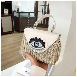 Détail du sac boîte en paille tressée avec œil brodé et franges en diamant