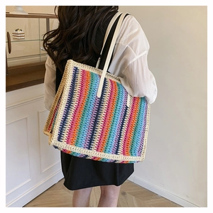 Rainbow striped woven tote bag shown on shoulder in a minimalist indoor setting