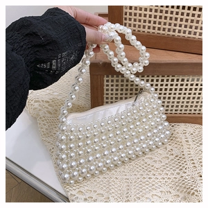 Close-up of elegant handmade white pearl beaded handbag with silver zipper and handle