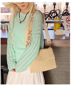 Detail of beige straw crossbody bag featuring a colorful geometric patterned wide strap