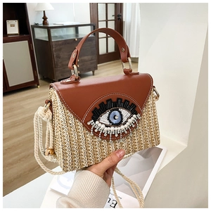 Détail du sac panier tressé avec rabat en cuir et broderie de perles œil grec
