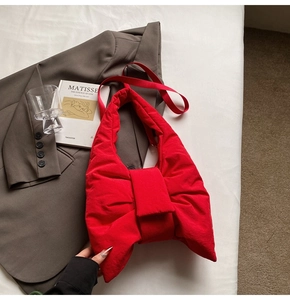 Detail of red quilted nylon bow tote bag on bed with lifestyle aesthetic accessories