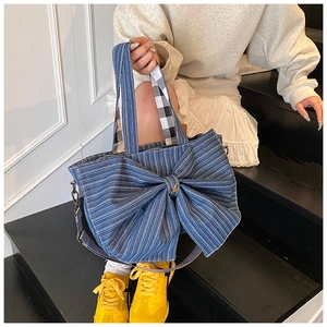 Detail of blue denim tote bag featuring a large bow and white vertical stripes