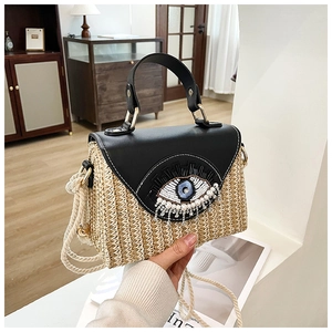 Détail du sac boîte en paille avec bordure en cuir et décor œil perlé brodé
