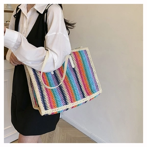 Side view of rainbow striped woven tote bag with slim cream faux leather handles