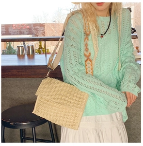 Detail of a beige straw crossbody bag with a geometric pattern woven wide shoulder strap