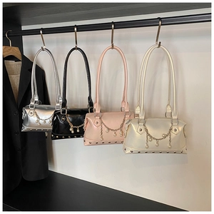 Detail von vier bunten Handtaschen mit Perlenmetallketten und Nietakzenten an einem Gestell