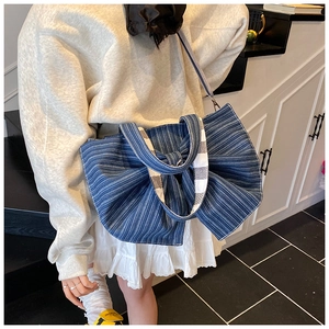 Detail of blue striped denim tote bag featuring large bow and checkered strap