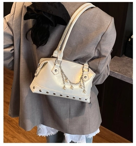 Close-up of cream tote bag with pearl chain detail and silver studs on grey blazer