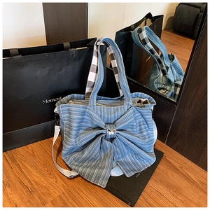 Close-up of blue denim tote bag with a large bow, metal butterfly and checkered handle