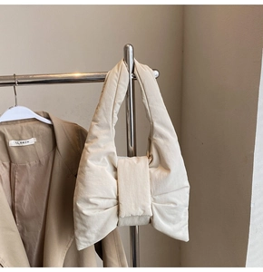 Detail of apricot puffer tote bag with oversized bow design on a metal hanger