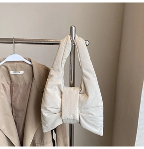 Detail of a creamy beige padded tote bag with a unique bow-shaped quilted design