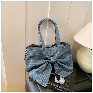 Macro shot of light blue striped canvas tote with a large bow and silver butterfly pin