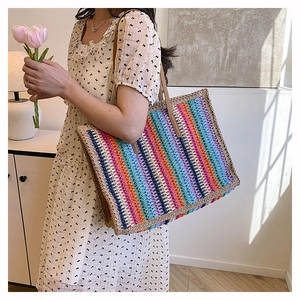 Detailed view of colorful rainbow straw tote bag with brown leather handles and vibrant stripes