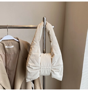 Detail view of a cream puffer tote bag featuring a 3D oversized bow design and padded fabric