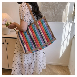 Rainbow striped woven tote bag with brown leather straps shown on a female model